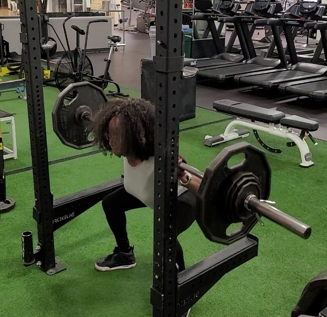 Person performing a barbell squat in a gym.